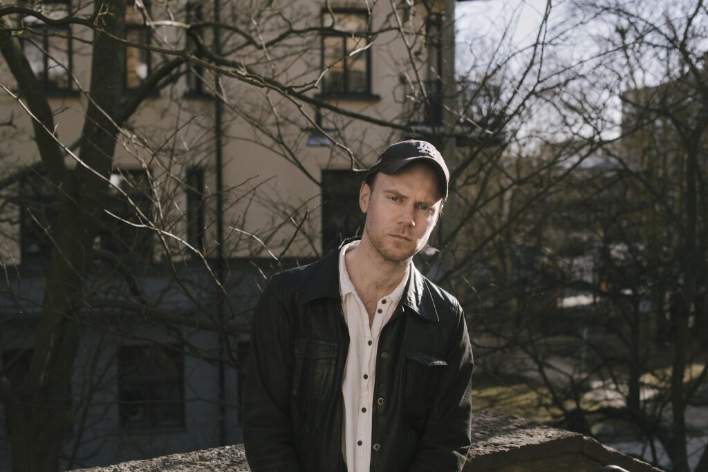 Tom Malmquist, I hvert øyeblikk er vi fremdeles i live Bildet viser Tom Malmquist som står i en bakgård.