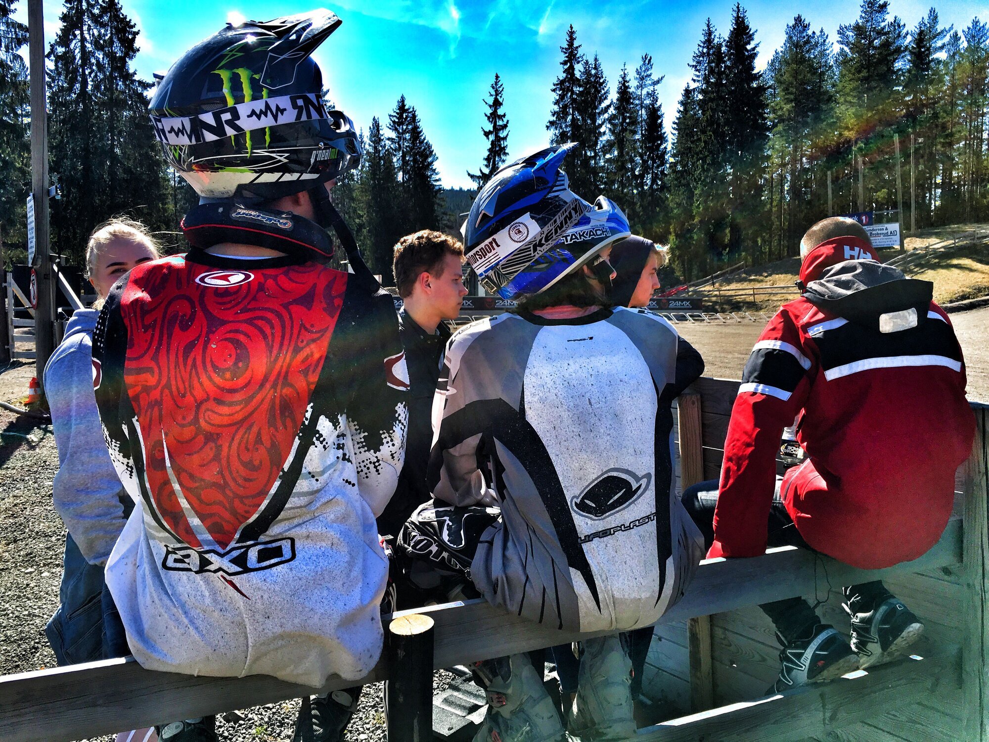 Crosskjøring Bildet viser noen ungdommer som sitter på et gjerde med ryggen til og MC-hjelmer på hodet