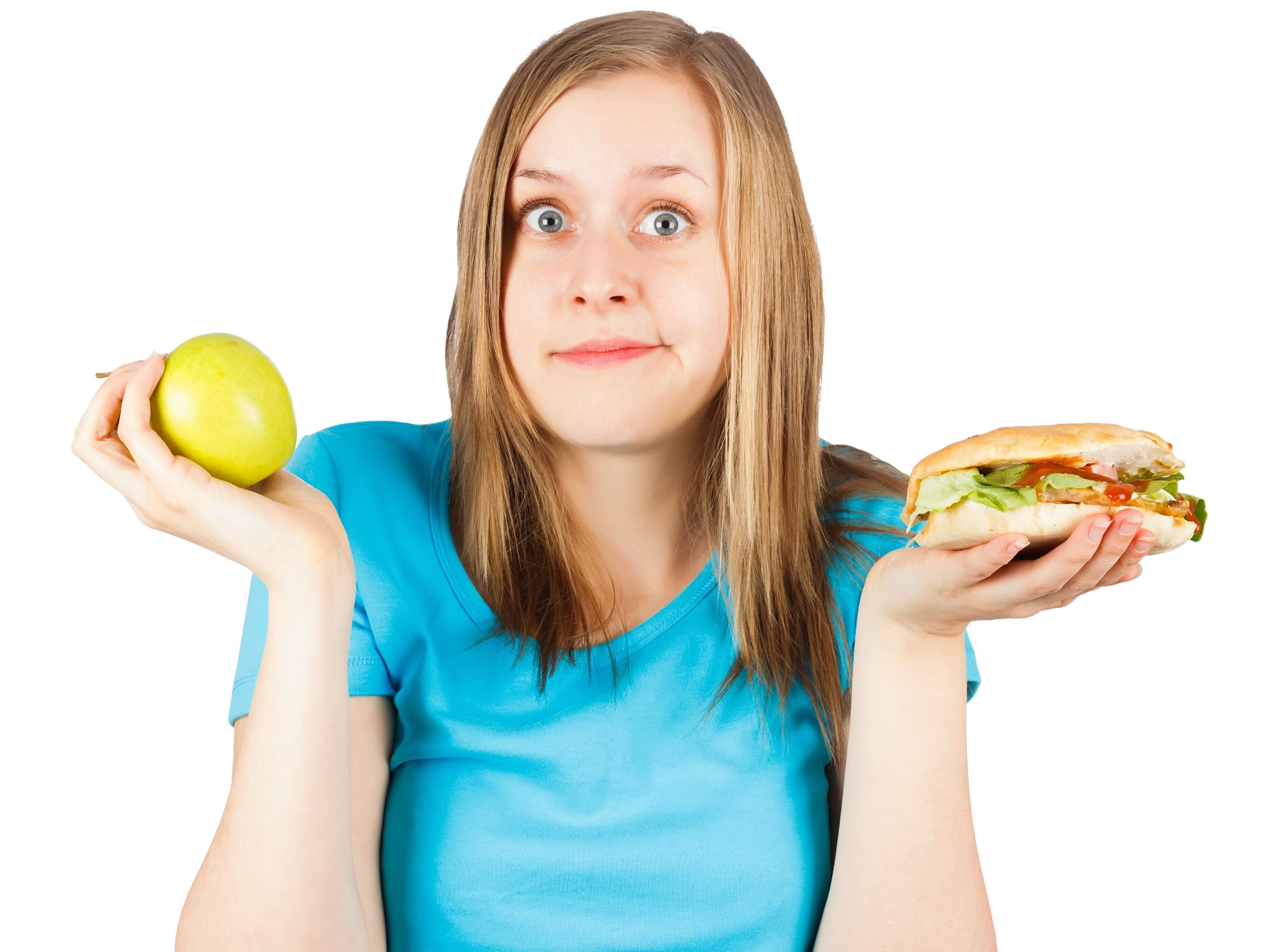Matvalg En jente holder en hamburger i ene hånden og ett eple i den andre. Valgets kval
