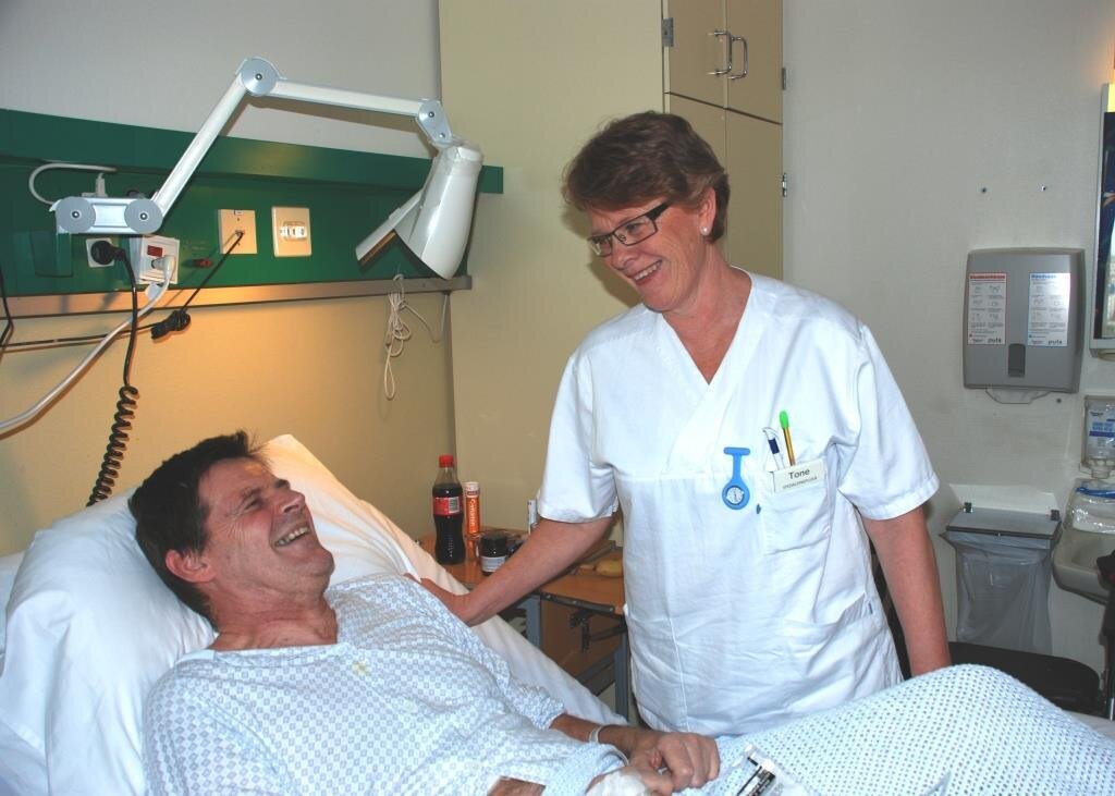 Bildet viser ALS-pasient Odd Arne B&oslash;e i en sykehusseng. Spesialsykepleier Tone Lahaug Nilsen st&aring;r ved siden av.