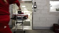 Ambulansepersonell i krisesituasjon En mann i ambulanseuniform løper inn på sykehuset med en båre