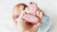 Føttene til nyfødt baby løftes opp