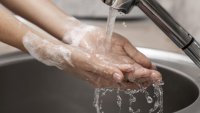 En person vasker hendene i rennende vann En person vasker hendene i rennende vann