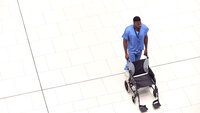Bildet viser sykepleier som triller en tom rullestol