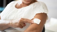 Bildet viser en kvinne som setter på et østrogen-plaster på overarmen.