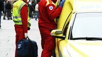 Bilde viser ambulansearbeidere som står utenfor ambulansen i et gatemiljø