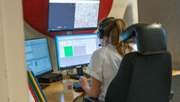 Bildet viser en telefonoperatør som sitter ved det medisinske nødsentralen foran mange dataskjermer.