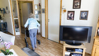 Bildet viser en eldre kvinne med rullator i sitt hjem