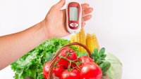Blodsukkermåler, grønnsaker Et blodsukkermålingsapparat holdes over en kurv med grønnskaer