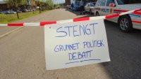 Bildet viser en avsperret vei med et skilt hvor det står "Stengt på grunn av politisk debatt" Bildet viser en avsperret vei med et skilt hvor det står "Stengt på grunn av politisk debatt"