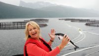 Fiskeoppdrett Torill er ute ved et fiskeoppdrettsanlegg. Hun holder en fisk i hånden.