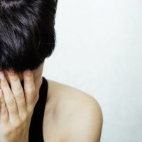 Bildet viser en ung dame eller jente som fortvilet holder hodet i hendene.