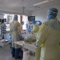 Bildet viser sykepleiere ved en pasient som er innlagt for covid-19, i en såkalt covid-kohort