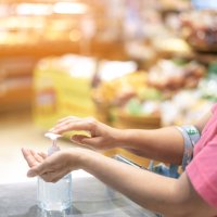 Bildet viser en dame som tar på håndsprit i en butikk