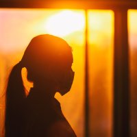 Kvinne med munnbind i motlys