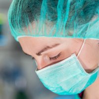 Bildet viser nærbildet av en kvinne med munnbind og hårnett.