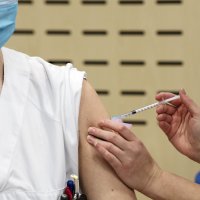 Bildet viser en helsearbeider som får koronavaksine.