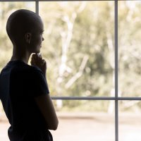 Bildet viser en kvinne med kreft som titter ut av vinduet.