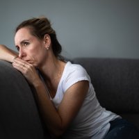 Bildet viser en kvinne som ser tankefullt ut i luften