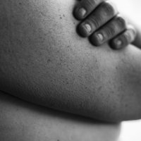 En kvinne holder armene over bysten