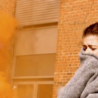 Bildet viser en skadet kvinne med et pledd rundt seg. Det er røykskyer rundt henne.