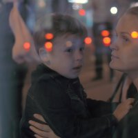 Bildet viser en kvinne som stirrer ut av et vindu med et barn på fanget