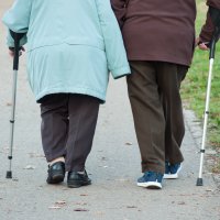 Et eldre par med spaserstokk går tur