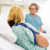 Sykepleier ser på nyfødt og moren