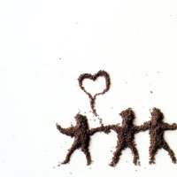 Bildet viser tre dansende figurer tegnet opp i sand med en prateboble mellom seg formet som et hjerte