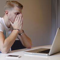 En sliten, ung mann ser på en dataskjerm