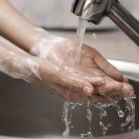 En person vasker hendene i rennende vann