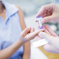 Bildet viser hender som tar en crp-prøve av en ung jente.