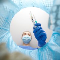 Bildet viser en sykepleier som kaster medisinsk utstyr i søppelet