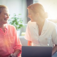 En sykepleier og en pasient smiler til hverandre