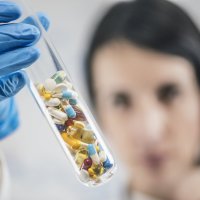 Bildet viser en kvinne som holder opp et glassrør med piller.