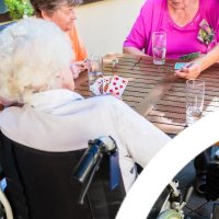 Bildet viser sykehjemsbeboere som spiller kort ute