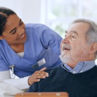 Bildet viser en melaninrik sykepleier som kommuniserer med en pasient