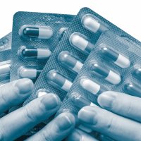 Bildet viser to hender som holder flere brett med piller