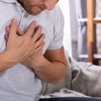 Mann med smerte i brystet holder hendene mot brystet.
