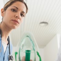 Sykepleier holder oksygenmaske.