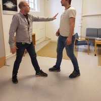 Bilde av to menn i rollespill. Den ene spiller behandler mens den andre spiller pasient. Behandleren forsøker å avverge vold.