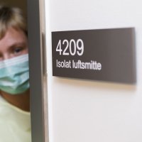 Kvinne i beskyttelsesytstyr utenfor isolat.